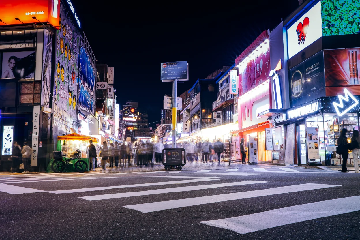 Busy nightlife street in Myeongdong Seoul with neon lights, food stalls, and crowds near a central korea hotel.