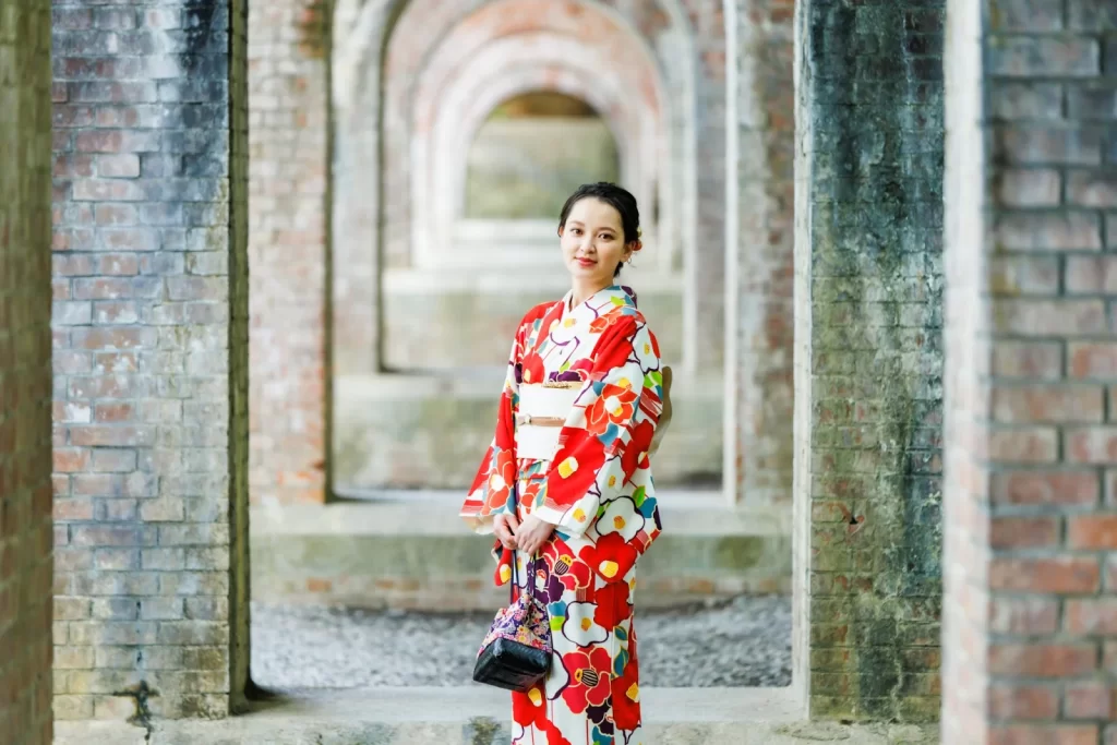 Woman in red kimono under historic brick arches in Kyoto, a cultural experience near your Kyoto hotel.
