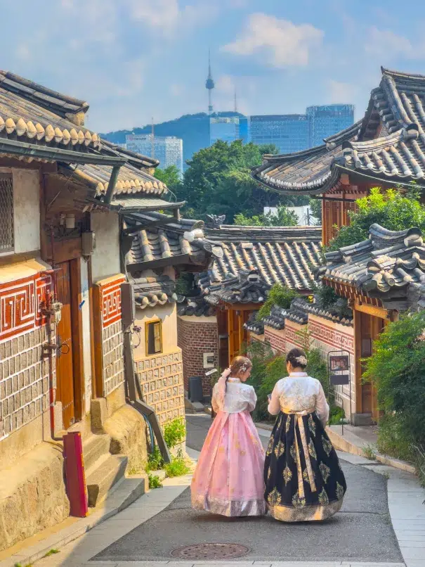 Ladies wearing hanbok strolling down Bukchon Hanok Village, a heritage site within easy distance of many Seoul Hotels