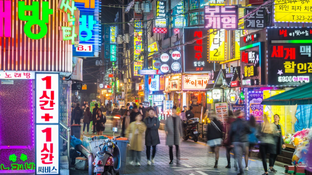 Busy neon-lit street in Seoul nightlife district, a vibrant scene for travellers on a long stay package.