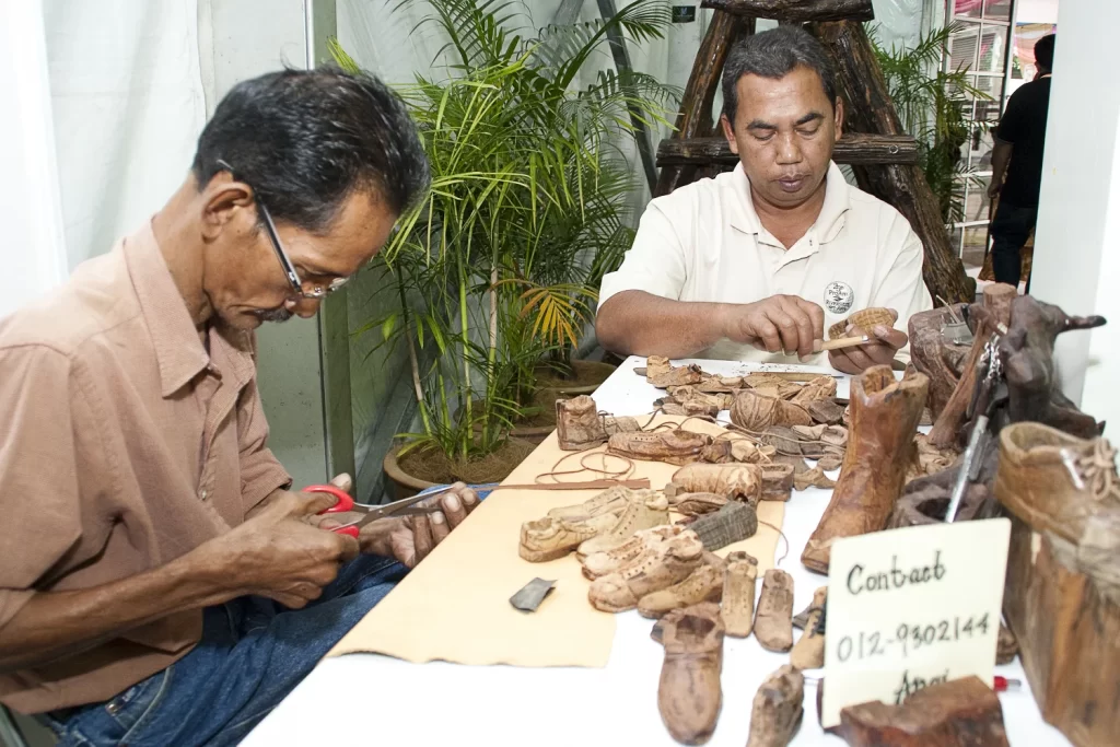 Locals carving shoe-shaped wood souvenirs