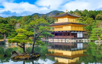 Kinkaku-ji Golden Pavilion in Kyoto, Japan, reflected on the lake with surrounding trees and mountains – a must-visit near your Kyoto hotel